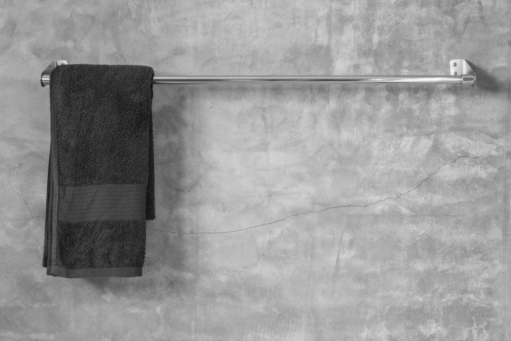 Stainless steel towel on grey cement wall with towel in bathroom