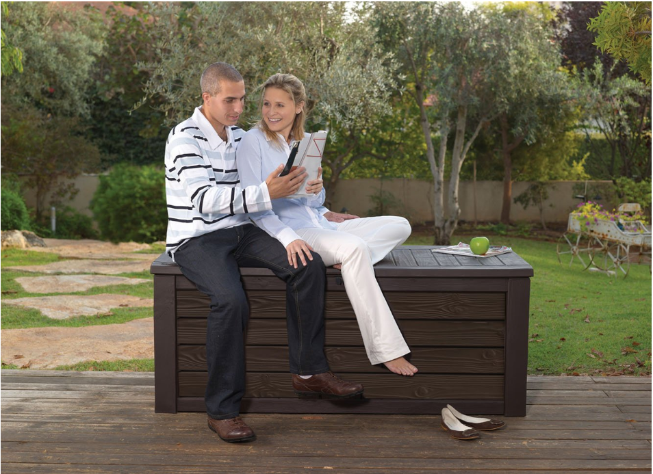 A couple sitting on an outdoor storage bench