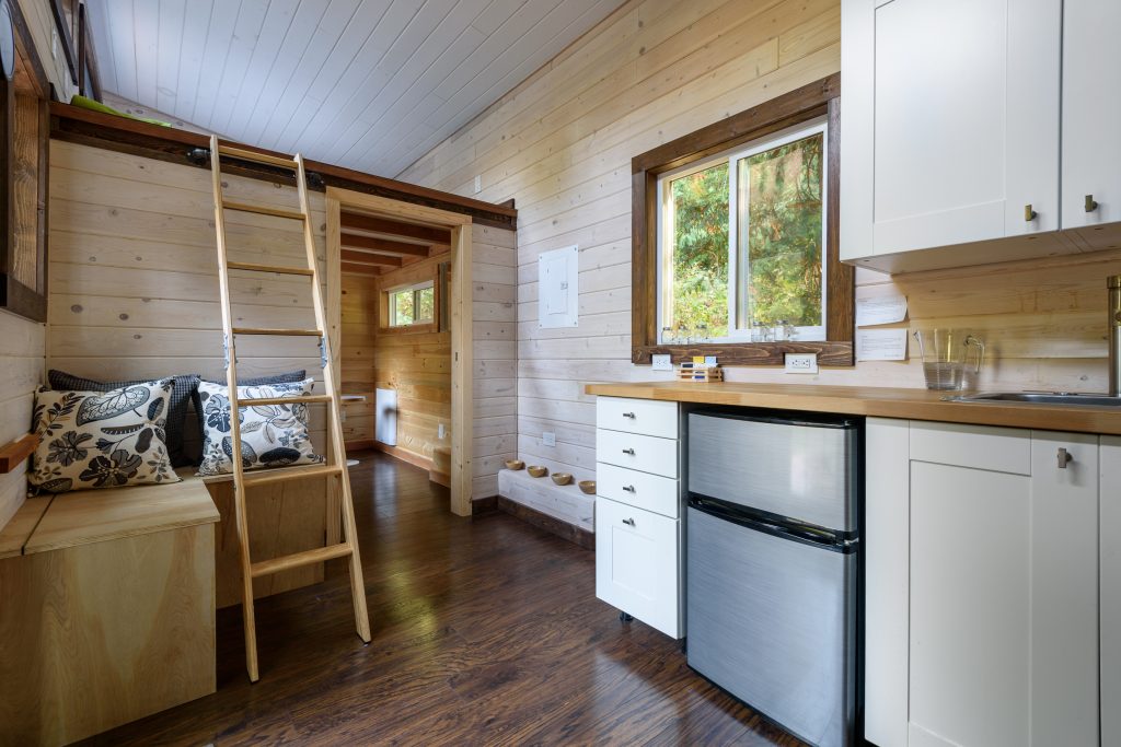 Interior design of a dining room and kitchen in a tiny rustic log cabin.