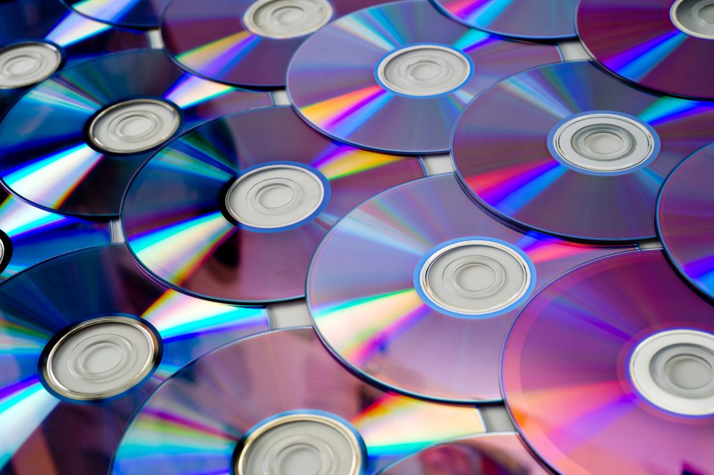 Background of CD and DVD discs laid out on a flat surface