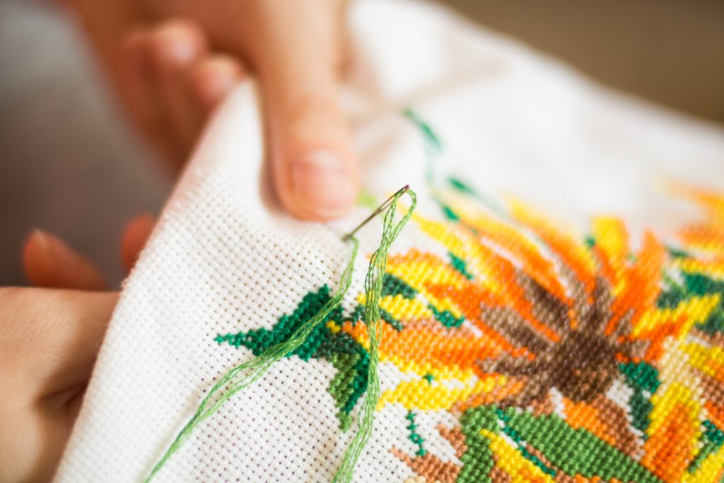The process of working embroidery. Hands girls embroider pattern of flowers. Embroidery and cross stitch accessories. Close-up.
