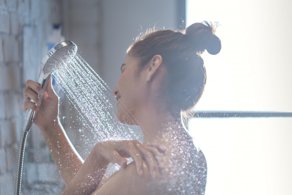 Asian woman is taking a shower and rubbing her shoulders. 